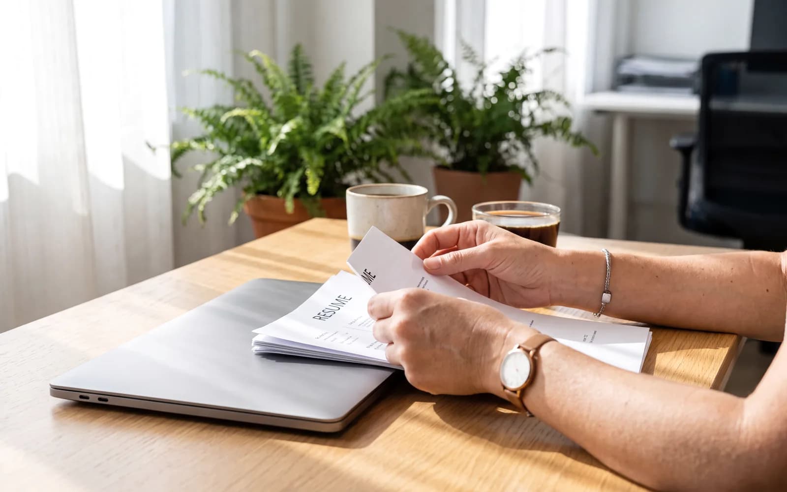 Hands reviewing printed resumes at a desk